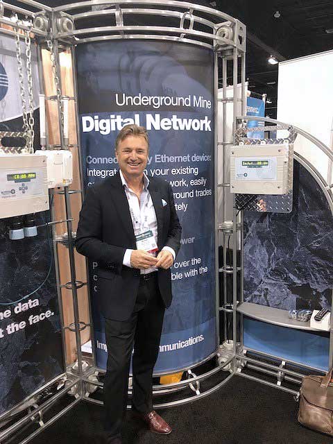 Mike Gribbons standing in front of the Maestro Digital Mine booth at the SME Conference
